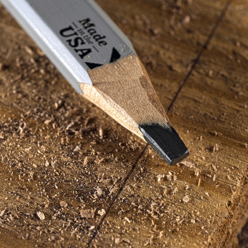 Carpenter pencil resting on wood with a line drawn across it.