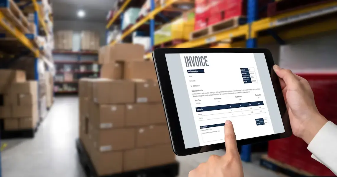 Person holding iPad in warehouse looking at an invoice