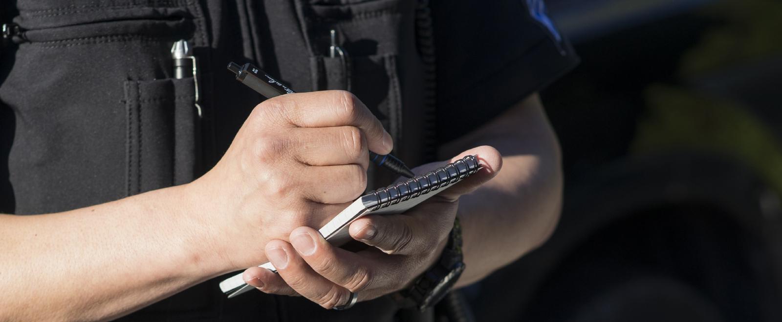 Officer writing in notebook with all weather pen.