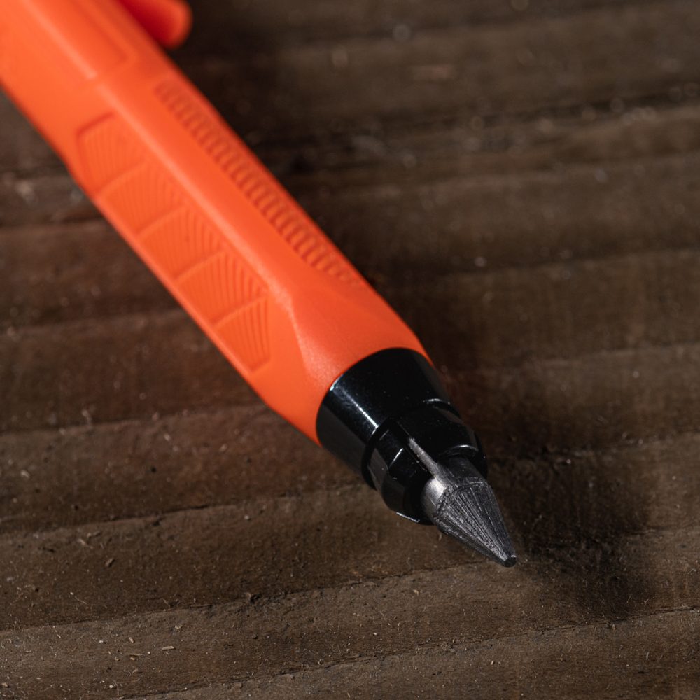 Gravity-fed lead holder sitting on wood, close up of the tip.