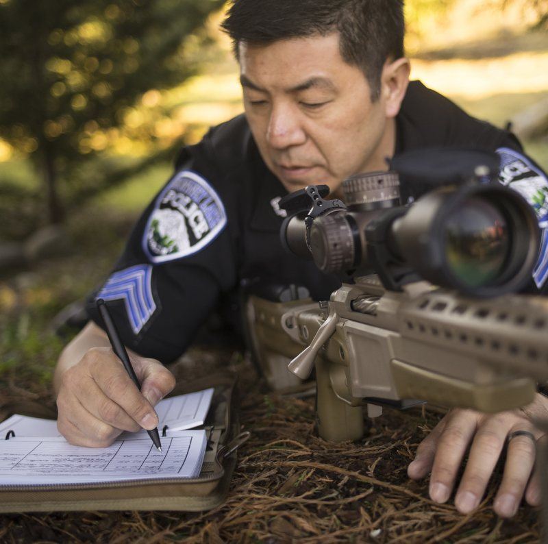 Officer taking notes after looking through his scope.