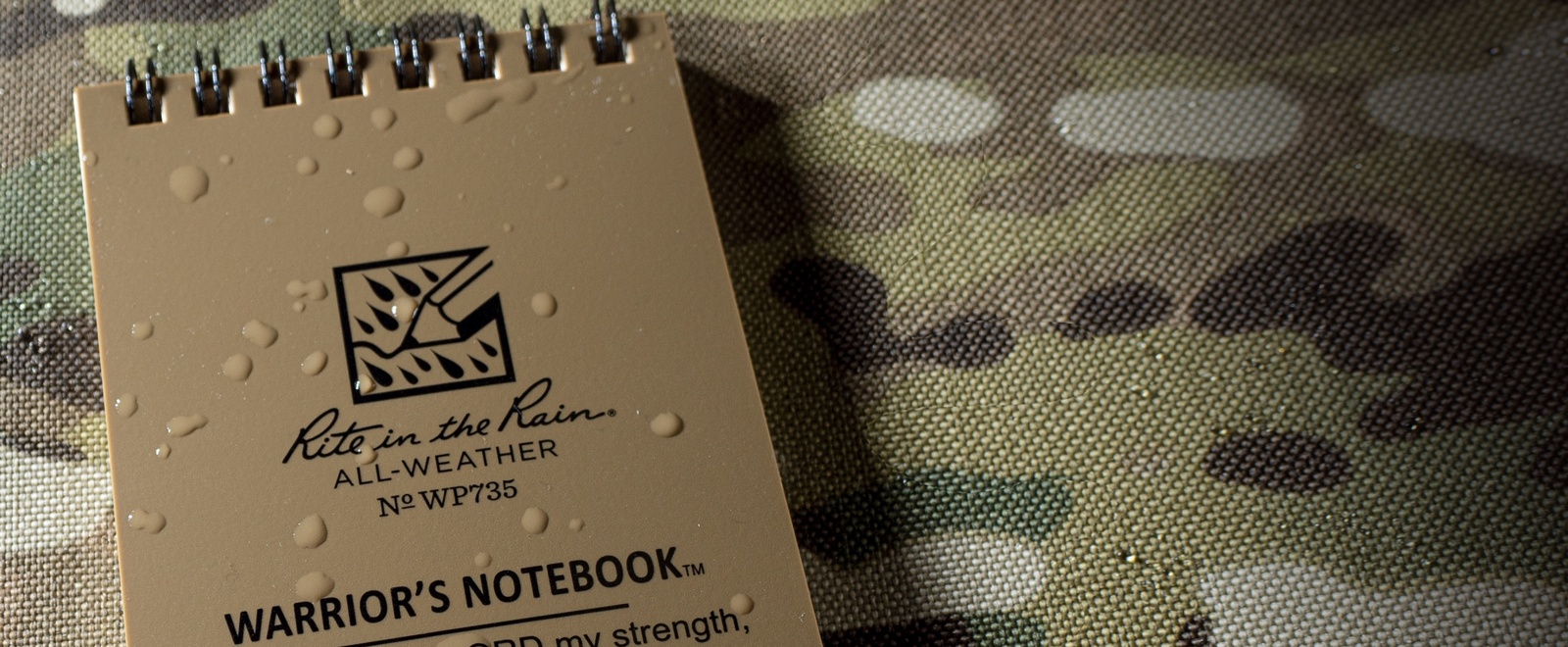 Wet notebook sitting on camouflaged material.