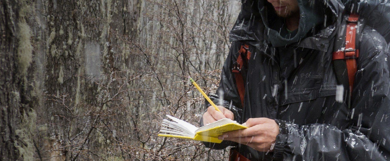 Student writing on book in the pouring rain.