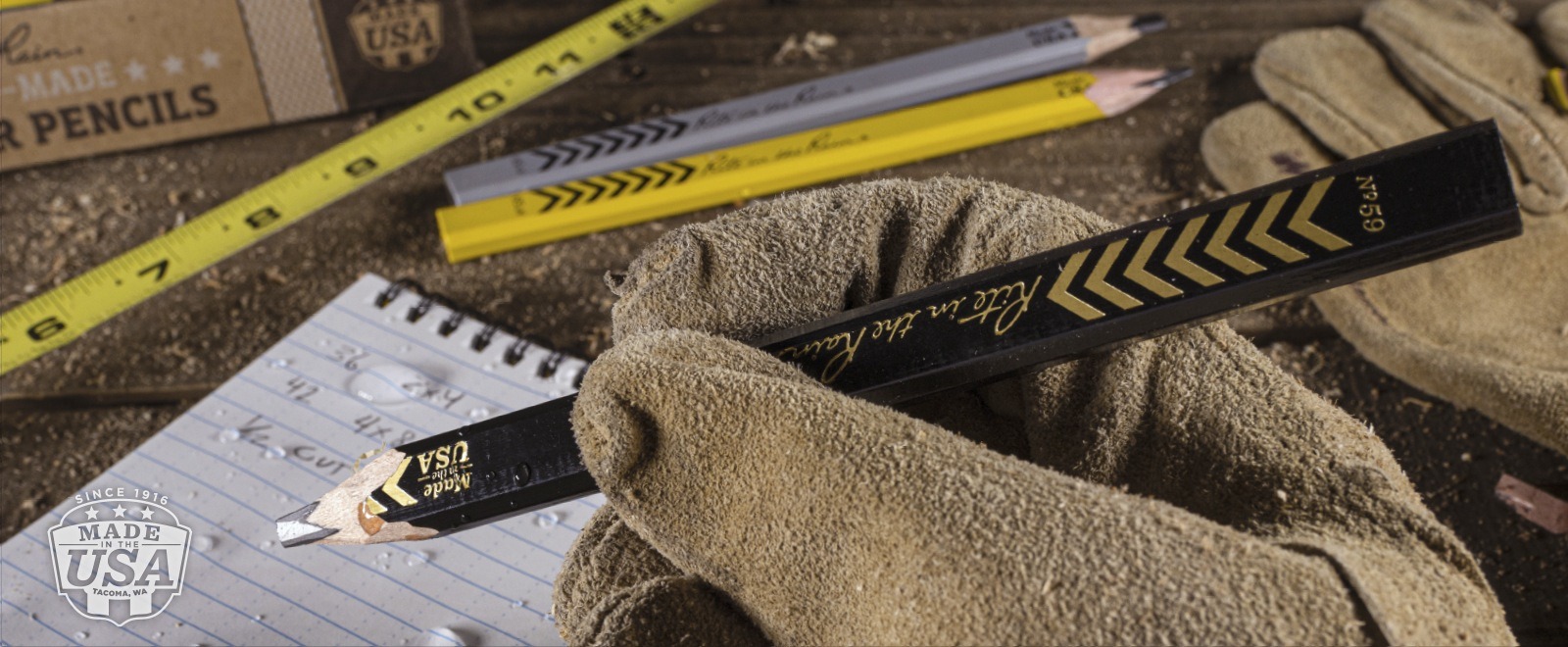 Hand in a work glove holding a Carpenter pencil.