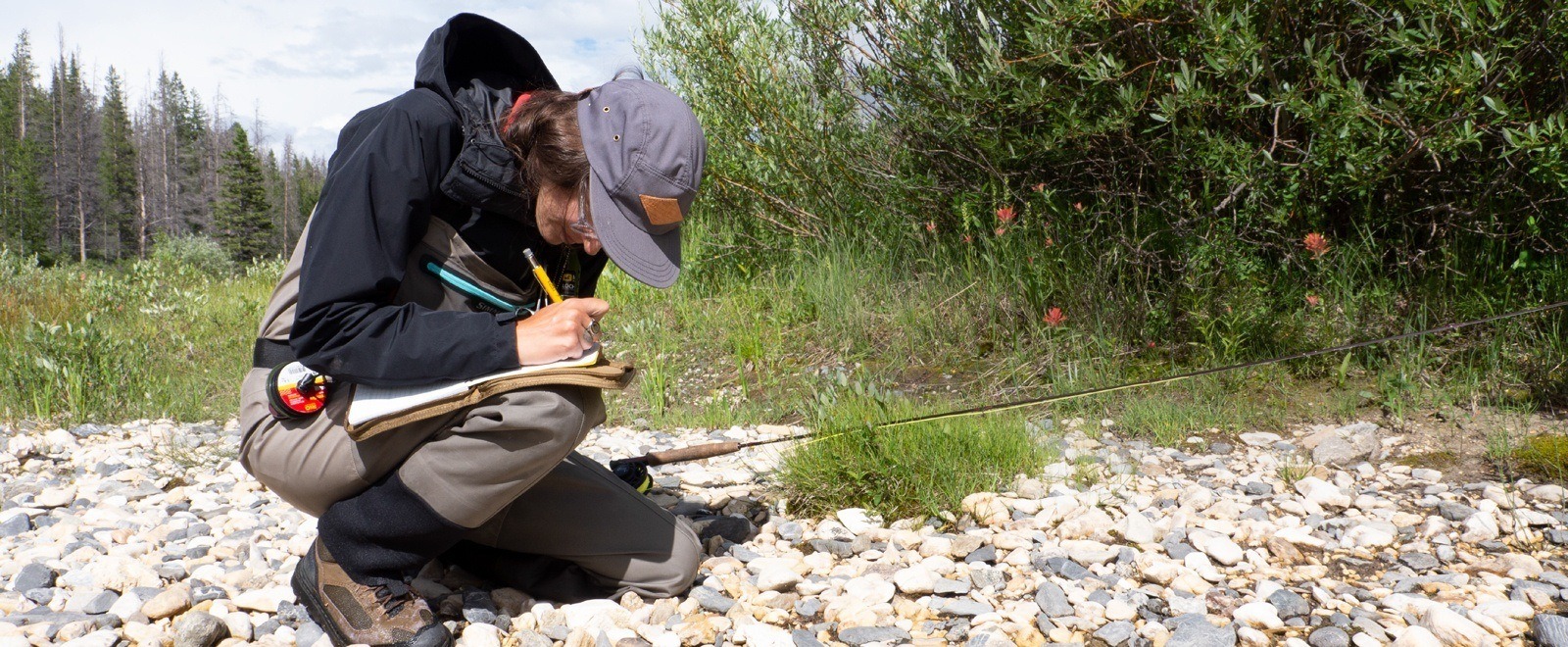 Fishing guide writing in a notebook held in a cover.