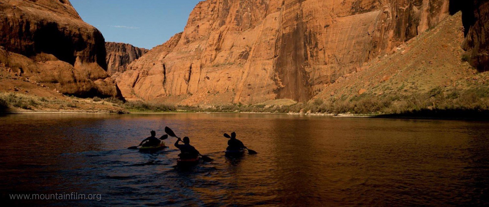 Kayakers paddling through a canyon.